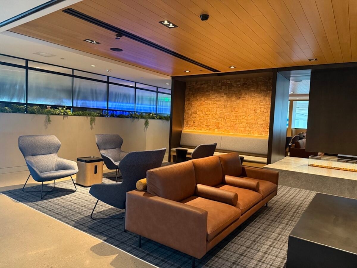 Modern lounge area with a brown leather sofa and blue accent chairs around a dark coffee table in a contemporary lobby.