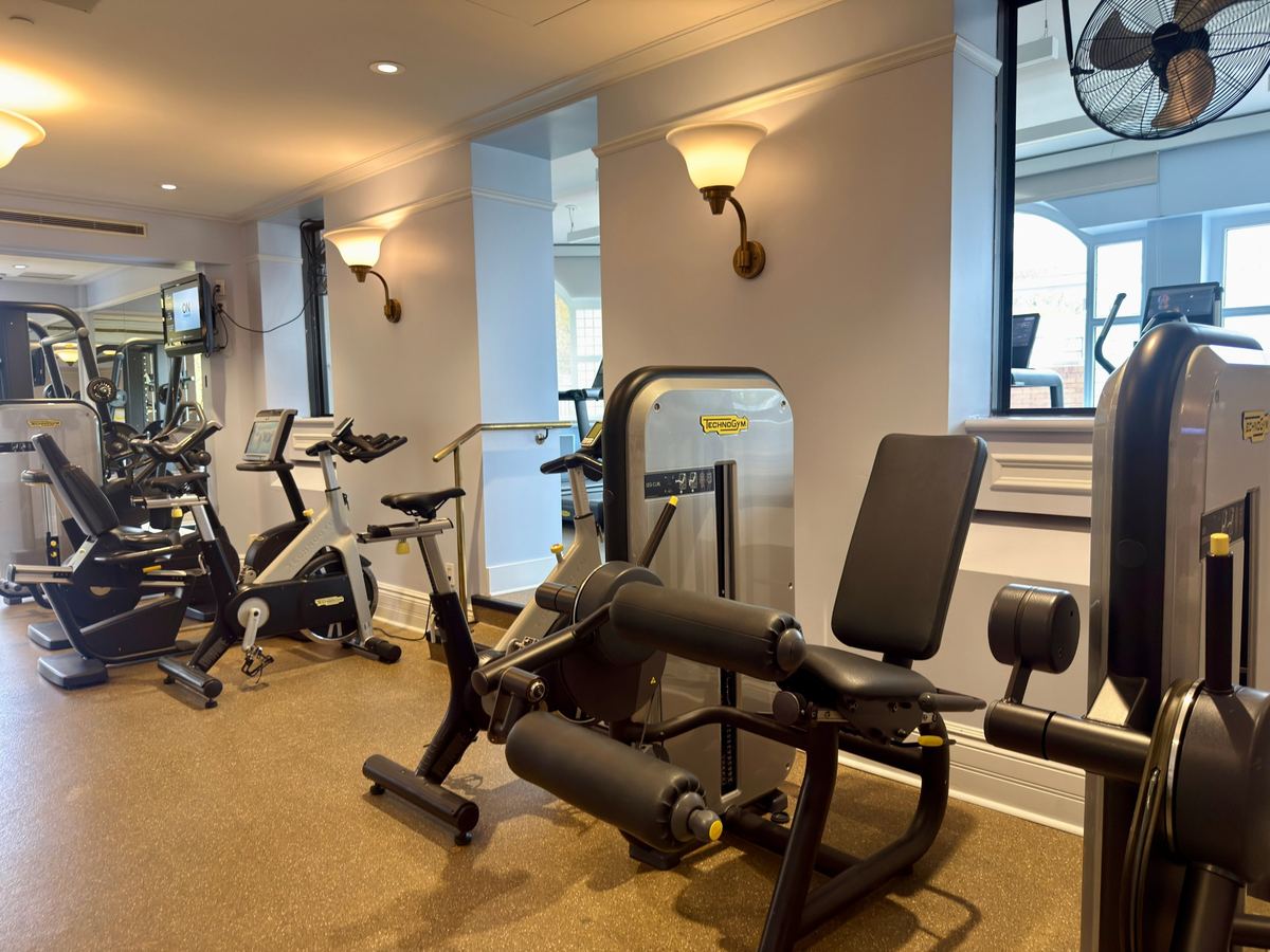 chateau-frontenac-gym - Tomo Travel & Camping A well-lit gym with treadmills, stationary bikes, and weight machines along cream-colored walls.