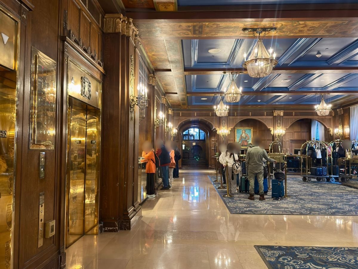 chateau-frontenac-lobby - Tomo Travel & Camping Elegant hotel lobby with a blue coffered ceiling, chandeliers, and a marble floor; guests queue at the front desk.