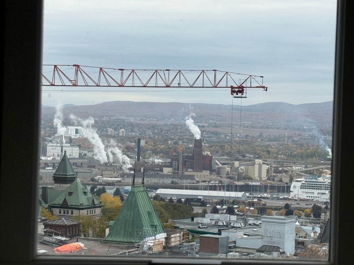 chateau-frontenac-room-view - Tomo Travel & Camping City skyline viewed from a window with a red construction crane spanning the top and smokestacks in the foreground.