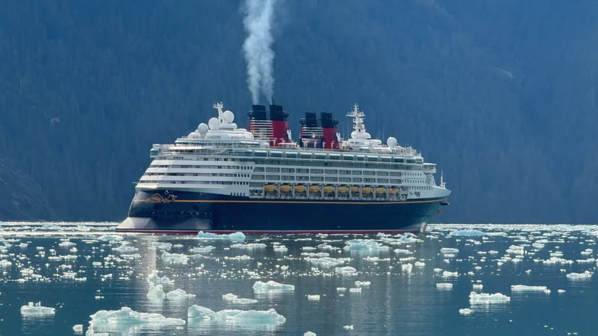 Disney Wonder cruise ship sailing through floating ice in an Alaska fjord