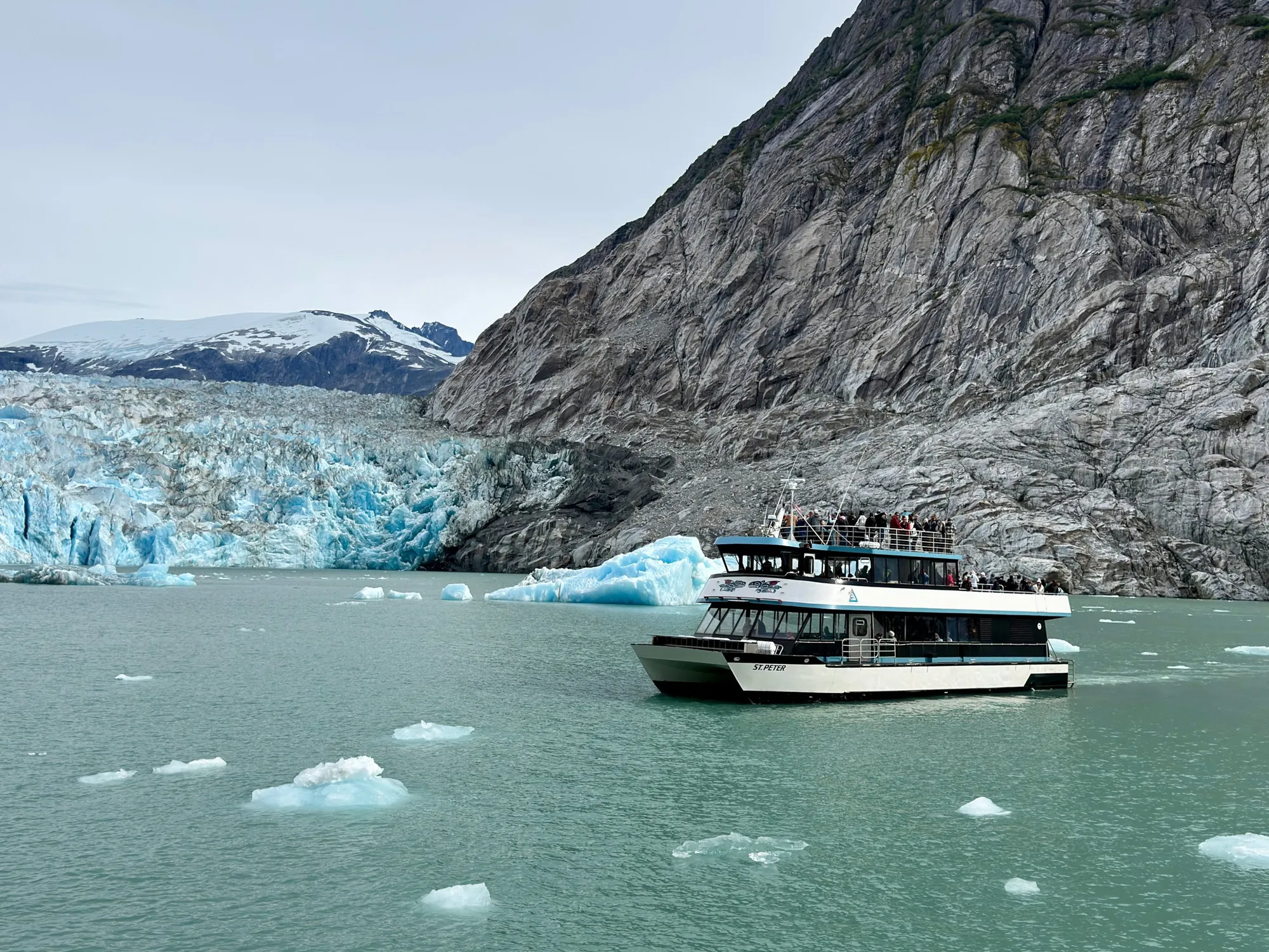 Glacier Explorer excursion boat near a blue tidewater glacier with floating ice in Alaska
