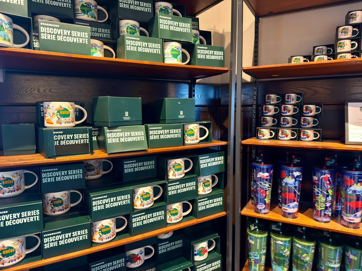 starbucks-quebec-mugs - Tomo Travel & Camping Shelf displays Starbucks Discovery Series Quebec mugs in green boxes on wooden shelves.